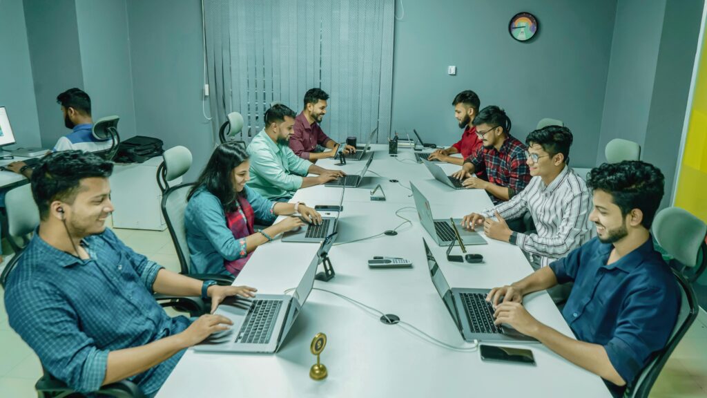 Group of professionals collaborating in a modern office setting on laptops and digital devices.